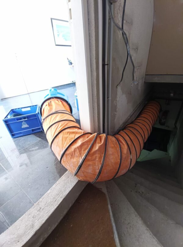 Installation technique d'une gaine de ventilation orange traversant les pièces pour acheminer l'air sec vers les zones sinistrées.