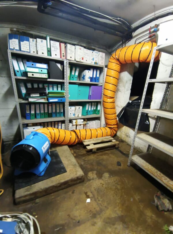 Chantier d'assèchement professionnel en sous-sol avec caisson ventilé et réseau de gaines pour traiter l'humidité structurelle.