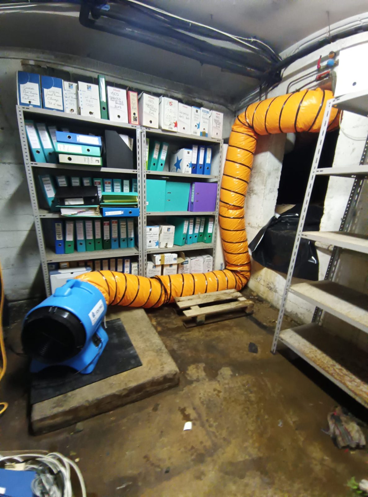 Chantier d'assèchement professionnel en sous-sol avec caisson ventilé et réseau de gaines pour traiter l'humidité structurelle.